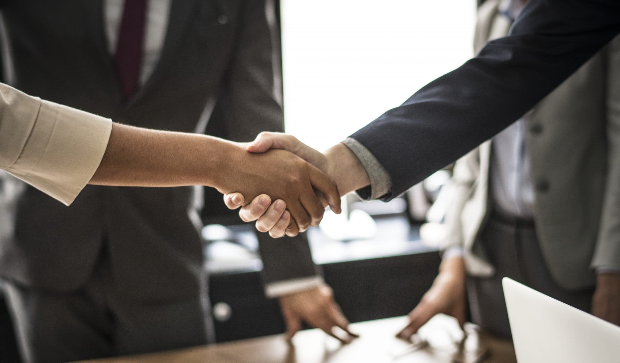 Two people shaking hands across a desk